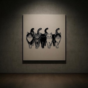 May include: A framed artwork featuring five stylized black and white cat illustrations. The cats are depicted in various poses, with different markings and patterns. The artwork is displayed on a neutral-colored wall.
