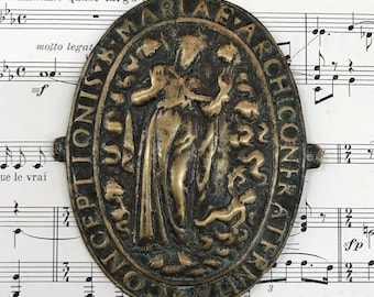 May include: An oval-shaped, bronze-colored metal pendant with a raised image of a woman holding a baby. The pendant is inscribed with the words "CONCEPTIONIS MARIÆ ARCHICONFRATER", which is Latin for "Confraternity of the Immaculate Conception of Mary".