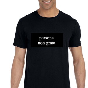 May include: A black t-shirt with the text "persona non grata" printed in white on a black rectangle.