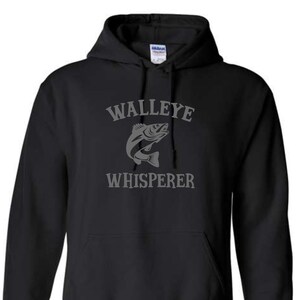 K&ouml;nnte beinhalten: Schwarzer Kapuzenpullover mit einem grauen Aufdruck eines Zanderfisches und dem Text "Walleye Whisperer".