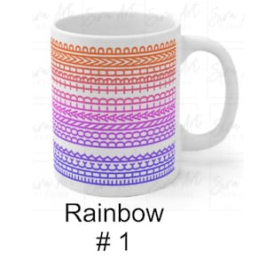 Può includere: Tazza in ceramica bianca con un design arcobaleno. Il design presenta bande orizzontali di motivi arancioni, rosa, viola e blu. La tazza ha un manico bianco e il testo "Rainbow #1" in basso.