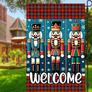 Puede incluir: Una bandera de jardín decorativa con tres soldados cascanueces coloridos sobre un fondo azul con copos de nieve. La bandera tiene un borde a cuadros rojo y negro y la palabra "WELCOME" en escritura blanca.