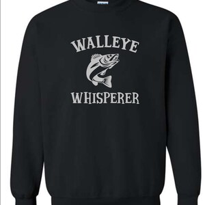 K&ouml;nnte beinhalten: Schwarzer Pullover mit einem wei&szlig;en Aufdruck eines Zanders und dem Text "WALLEYE WHISPERER".
