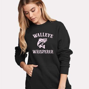 K&ouml;nnte beinhalten: Schwarzer Pullover mit einem rosafarbenen Walleye-Fisch-Motiv und dem Text "WALLEYE WHISPERER".
