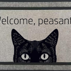 Könnte beinhalten: Rechteckige Fußmatte mit grauem Hintergrund und schwarzem Rand. Der Text "Welcome, peasants" steht über dem Kopf einer schwarzen Katze mit weißen Augen. Ein lustiger und skurriler Einrichtungsgegenstand.