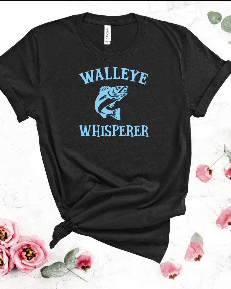 K&ouml;nnte beinhalten: Schwarzes T-Shirt mit einem blauen Walleye-Fisch-Motiv und dem Text "WALLEYE WHISPERER".