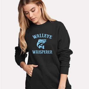 K&ouml;nnte beinhalten: Schwarzer Pullover mit einem blauen Walleye-Fisch-Motiv und dem Text "WALLEYE WHISPERER".