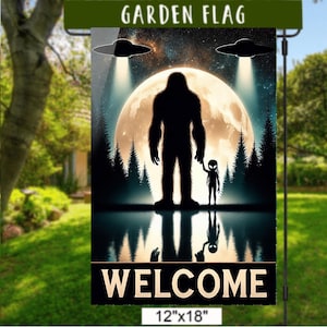 Puede incluir: Una bandera de jardín de 30 cm x 46 cm con una silueta de Bigfoot tomados de la mano con un extraterrestre, bajo una luna llena y dos ovnis. La palabra "WELCOME" está en la parte inferior. La bandera se muestra en un soporte de metal negro.