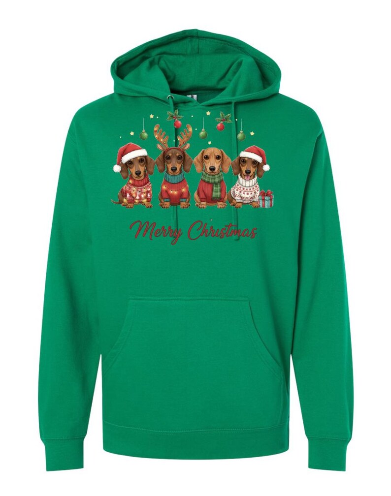 May include: Green hooded sweatshirt featuring a festive design. The graphic includes four dachshunds dressed in Christmas attire, with Santa hats, reindeer antlers, and sweaters. The words "Merry Christmas" are written in red script below the dogs.