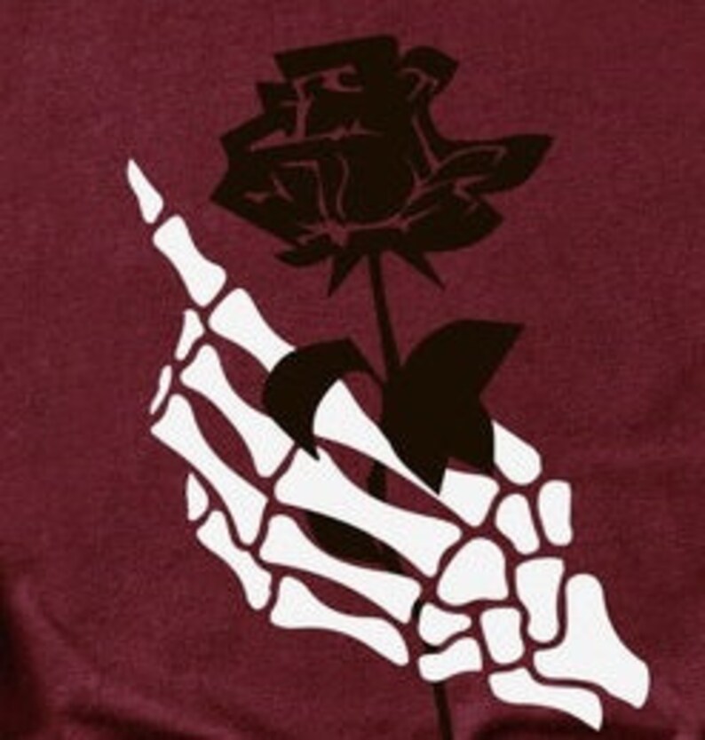 Peut inclure: Une main squelettique blanche tenant une rose noire avec une tige et des feuilles.