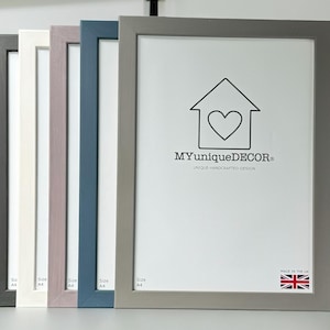 May include: Five different coloured picture frames, all size A4, with a white mount and a white background. The frame on the right is grey, the next is blue, the next is purple, the next is white, and the last is grey. The frame on the right has the text "MYuniqueDECOR" and "UNIQUE HANDCRAFTED DESIGN" on it. The frame also has a small British flag in the bottom right corner with the text "MADE IN THE UK".