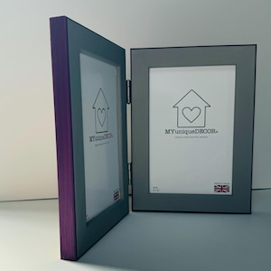 Puede incluir: Un marco de fotos doble con acabado de madera púrpura y gris. El marco tiene bisagras y un logotipo de corazón con el texto "MYuniqueDECOR." El marco mide 10,16 x 15,24 cm.