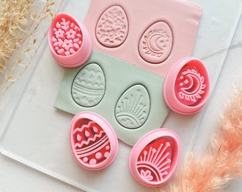 May include: Set of nine pink plastic Easter egg cookie cutters with various designs, including floral, geometric, and crescent moon patterns.