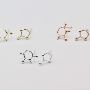 Op de afbeelding: Drie paar oorbellen in goud, rosé goud en zilver, elk met een moleculair structuurontwerp.