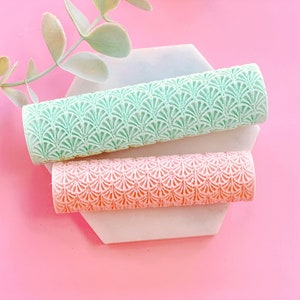 May include: Two silicone rolling pins with a decorative pattern. The top rolling pin is light green and the bottom rolling pin is light pink.
