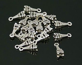 May include: A collection of small, silver-colored Eiffel Tower charms. Each charm has a loop at the top for stringing and is detailed with the tower's iconic structure. The charms are scattered on a dark surface.