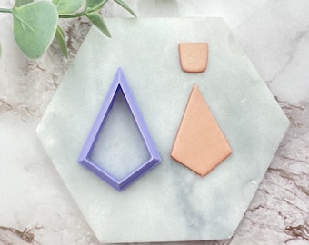 May include: A set of three polymer clay shapes, including a purple diamond-shaped cutter, a copper-coloured diamond, and a copper-coloured half-circle.