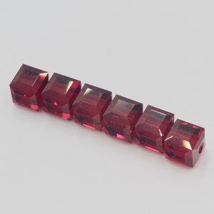 Peut inclure: Une rangée de sept perles carrées en verre rouge.