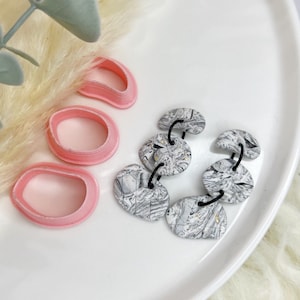 Op de afbeelding: Een paar oorbellen met een zwart-wit marmerpatroon. De oorbellen zijn gemaakt van polymer clay en hebben een unieke, abstracte uitstraling.