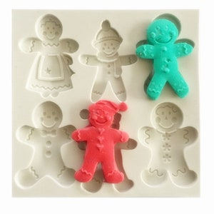 May include: A silicone mold for baking gingerbread people. The mold has six cavities, each shaped like a gingerbread person. The gingerbread people are decorated with different designs, including a star, a bow tie, a snowflake, and a heart.