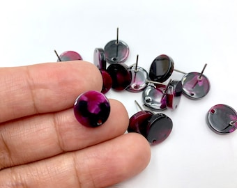May include: A group of round, black and pink earrings with silver posts. The earrings have a marbled effect.