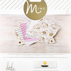 Puede incluir: Un paquete de hojas de papel decorativas de 15,24 x 15,24 cm con varios diseños, incluyendo florales, geométricos y a rayas. El paquete presenta una etiqueta circular dorada con el logo "Minc" y la marca "Heidi Swapp".
