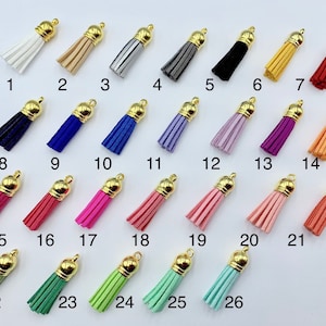 Peut inclure: Vingt-six pompons colorés avec des sommets dorés. Les pompons sont disposés en rangées et numérotés de 1 à 26.