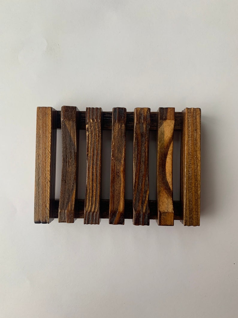 Puede incluir: Un jabonera de madera con un dise&ntilde;o de listones. La jabonera es de color marr&oacute;n oscuro y tiene un aspecto r&uacute;stico.