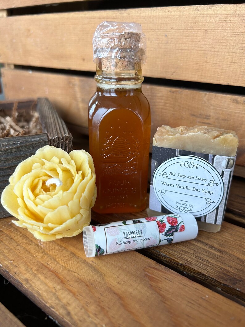 May include: A gift set with a small bottle of honey, a bar of soap, and a lip balm. The soap is labeled "Warm Vanilla Bar Soap" and the lip balm is labeled "Raspberry".