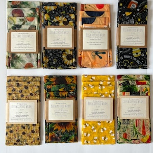 May include: A set of eight beeswax food wraps in various designs. The wraps are made of cotton fabric coated with beeswax, jojoba oil, and tree resin. The designs include sunflowers, bees, and a variety of fruits and vegetables. The wraps are reusable and biodegradable. The text on the labels reads "Beeswax Food Wraps" and "Set of 4".