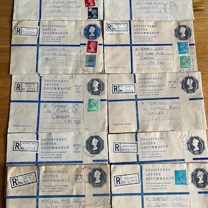 May include: A collection of eight vintage white registered letter envelopes with blue printed text and lines. Each envelope features a unique registration label, various postage stamps depicting Queen Elizabeth II, and handwritten addresses to H. Tempest Ltd in Cardiff.
