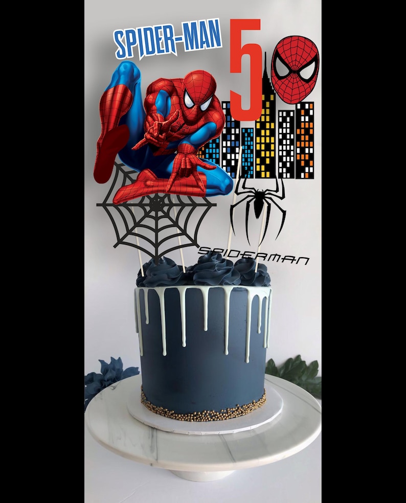 May include: A blue and white drip cake decorated with a Spiderman themed topper. The topper features a red and blue Spiderman figure, a black web, a red Spiderman head, and a red number 5.