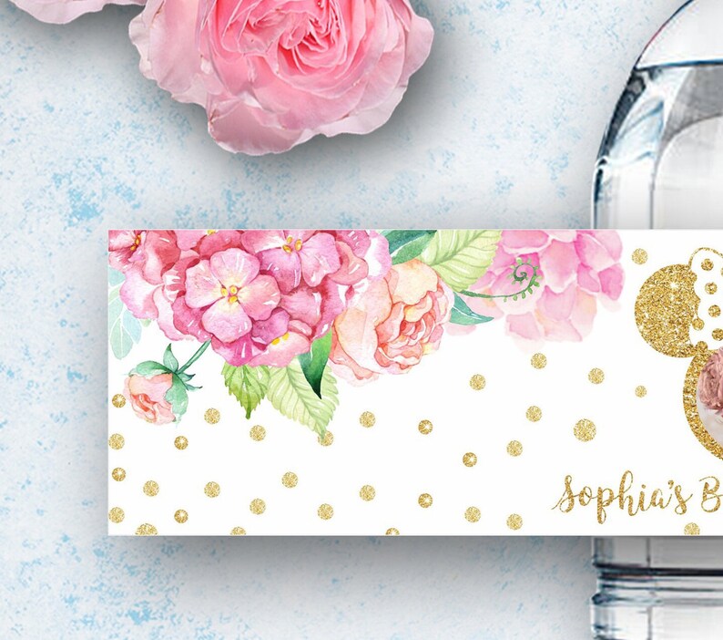 K&ouml;nnte beinhalten: Wasserflaschenetikett mit einem rosafarbenen Blumendesign und goldenen Glitzerpunkten. Der Text "Sophia's Birthday" befindet sich am unteren Rand des Etiketts.