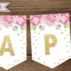 Puede incluir: Una pancarta blanca con dise&ntilde;os florales rosas y letras doradas con purpurina que deletrean "Happy". La pancarta est&aacute; decorada con puntos dorados con purpurina.