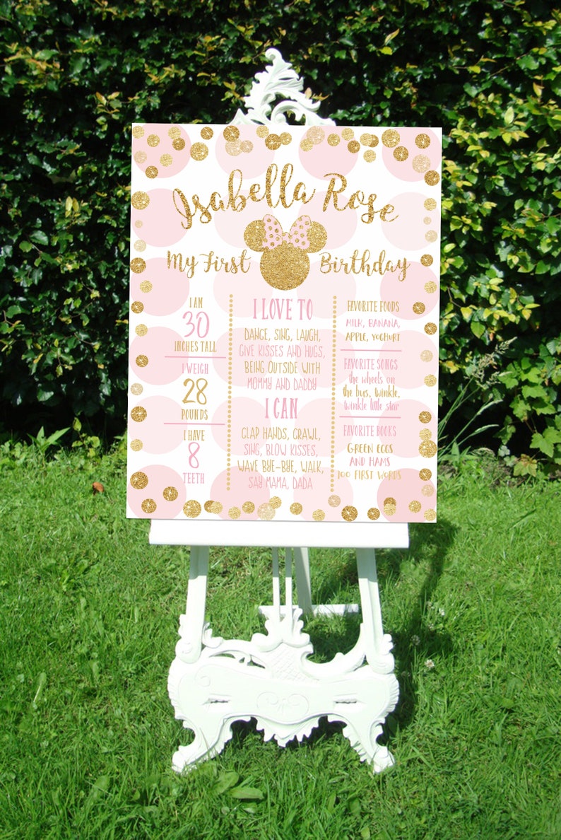 Puede incluir: Un cartel de primer cumplea&ntilde;os rosa y dorado con un gr&aacute;fico de la cabeza de Minnie Mouse. El cartel enumera la edad, la altura, el peso y la cantidad de dientes del ni&ntilde;o. Tambi&eacute;n incluye una lista de cosas que al ni&ntilde;o le encanta hacer, puede hacer y sus alimentos, canciones y libros favoritos.