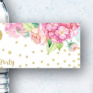 K&ouml;nnte beinhalten: Wasserflaschenetikett mit einem rosa-wei&szlig;en Blumendesign und goldenen Glitzerpunkten. Das Etikett lautet "Party".