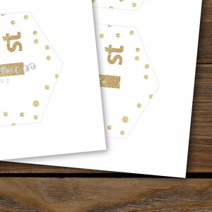 Puede incluir: Un "1er" de purpurina dorada con lunares dorados sobre un fondo blanco. El texto "Mama's Designs" est&aacute; en gris en la parte inferior del hex&aacute;gono.