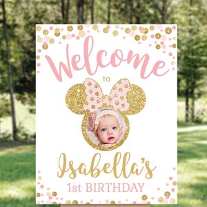 Pu&ograve; includere: Benvenuti al cartello del 1&deg; compleanno di Isabella con coriandoli glitter rosa e oro e una foto di una bambina con un vestito rosa e bianco.