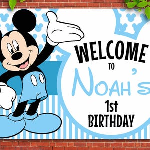 May include: A blue and white welcome sign featuring Mickey Mouse. The sign reads "Welcome to Noah's 1st Birthday".