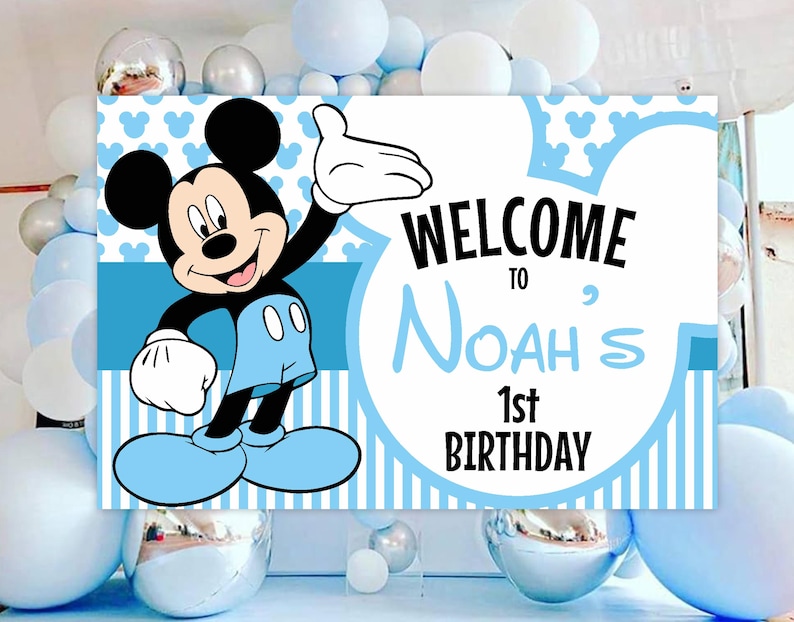 May include: Blue and white Mickey Mouse themed birthday party sign with the text "Welcome to Noah's 1st Birthday".