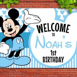 May include: A blue and white welcome sign featuring Mickey Mouse. The sign reads "Welcome to Noah's 1st Birthday".