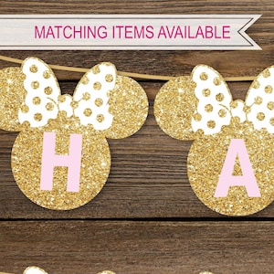 May include: Gold glitter Minnie Mouse ears with pink letters spelling "Happy" on a wooden background. Matching items available.