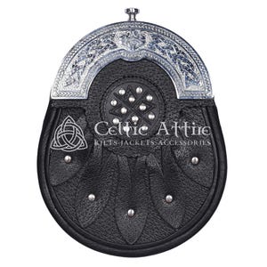 Pu&ograve; includere: Sporran in pelle nera con un cantle argentato ornato da disegni a nodo celtico. Lo sporran presenta un lembo decorativo con borchie argentate e un emblema a nodo celtico. Il testo "Celtic Attire" &egrave; visibile.