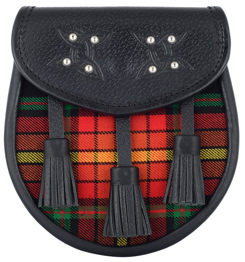 May include: A black leather sporran with three black tassels and a red, yellow, and green tartan design. The sporran has a flap with a Celtic knot design and silver studs.