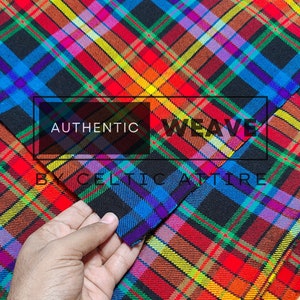 Puede incluir: Primer plano de una tela de cuadros coloridos con fondo negro. La tela está doblada por la mitad y la capa superior está ligeramente retraída para revelar la parte inferior. La tela está etiquetada como "Authentic Weave Celtic Attire".