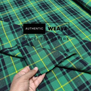 Op de afbeelding: Groen, zwart en geel geruit stof met de tekst "AUTHENTIC WEAVE BY CELTIC ATTIRE" op een wit label.