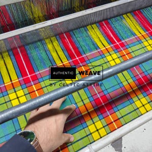 K&ouml;nnte beinhalten: Ein farbenfrohes Karostoff in Rot, Gelb, Gr&uuml;n und Blau wird auf einem Webstuhl gewebt. Der Text "AUTHENTIC WEAVE BY CELTIC ATTIRE" ist auf dem Stoff zu sehen. Eine Hand ber&uuml;hrt den Stoff.