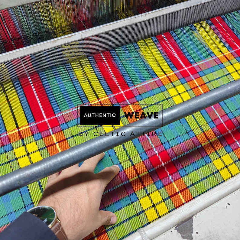 K&ouml;nnte beinhalten: Ein farbenfrohes Karostoff in Rot, Gelb, Gr&uuml;n und Blau wird auf einem Webstuhl gewebt. Der Text "AUTHENTIC WEAVE BY CELTIC ATTIRE" ist auf dem Stoff zu sehen. Eine Hand ber&uuml;hrt den Stoff.