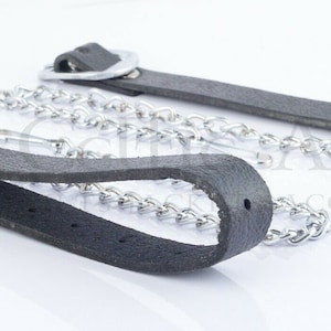 May include: Two black leather straps with metal rings and a silver chain. The straps are about 1 inch wide and the chain is about 1/4 inch thick.