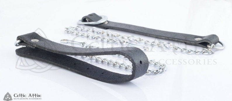 Pu&ograve; includere: Due cinturini in pelle nera con catena e ferramenta in metallo color argento. I cinturini hanno un'asola a un'estremit&agrave; e un anello di metallo all'altra. La catena &egrave; attaccata all'anello e all'asola.